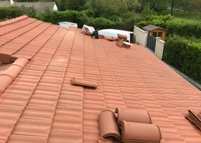 Vue a&eacute;rienne d'une toiture en tuiles terre cuite avec des tuiles empil&eacute;es pr&egrave;s du fa&icirc;tage
