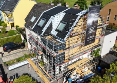 Vue a&eacute;rienne d'une maison mitoyenne &eacute;chafaud&eacute;e pendant la r&eacute;novation de sa toiture, avec couverture anthracite et b&acirc;che Lux Habitat