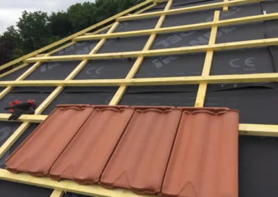 Tuiles terre cuite pos&eacute;es sur des liteaux au-dessus d'un &eacute;cran de sous-toiture, pose en cours