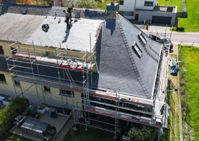 Deux couvreurs travaillant sur le fa&icirc;tage d'une toiture en ardoise, vue par drone