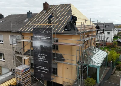 Vue a&eacute;rienne de couvreurs travaillant sur un voligeage neuf, &eacute;chafaudage et b&acirc;che Lux Habitat en fa&ccedil;ade