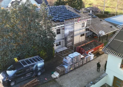 Vue a&eacute;rienne d'un chantier avec palettes de tuiles, camionnette Lux Habitat et toiture latt&eacute;e pr&ecirc;te &agrave; recevoir les tuiles