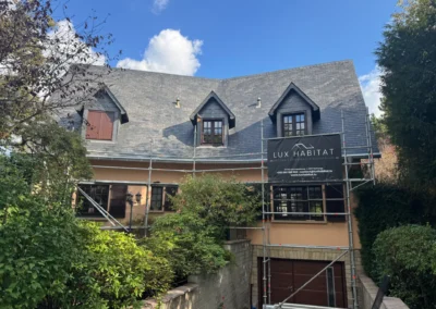 Maison traditionnelle avec toiture en ardoise et trois lucarnes, &eacute;chafaudage et b&acirc;che Lux Habitat en fa&ccedil;ade