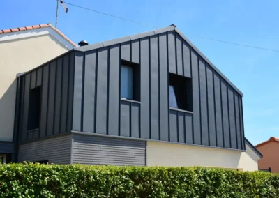 Maison moderne avec toiture et fa&ccedil;ade en zinc anthracite &agrave; joint debout, haie en premier plan