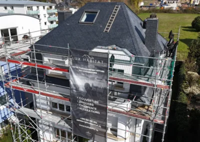 Vue par drone d'une toiture en ardoise avec lucarne, fen&ecirc;tre de toit et couvreurs sur l'&eacute;chafaudage