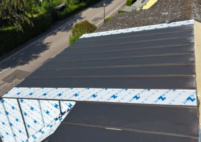 Vue a&eacute;rienne d'une toiture en cours de recouvrement avec des bacs m&eacute;talliques &agrave; joint debout anthracite pos&eacute;s sur un &eacute;cran de sous-toiture