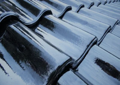 Gros plan sur des tuiles verniss&eacute;es anthracite mouill&eacute;es par la pluie