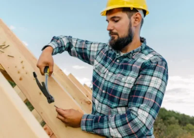 Charpentier avec casque jaune et chemise &agrave; carreaux travaillant sur une charpente en bois