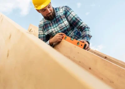 Charpentier avec casque jaune et chemise &agrave; carreaux travaillant sur une charpente en bois